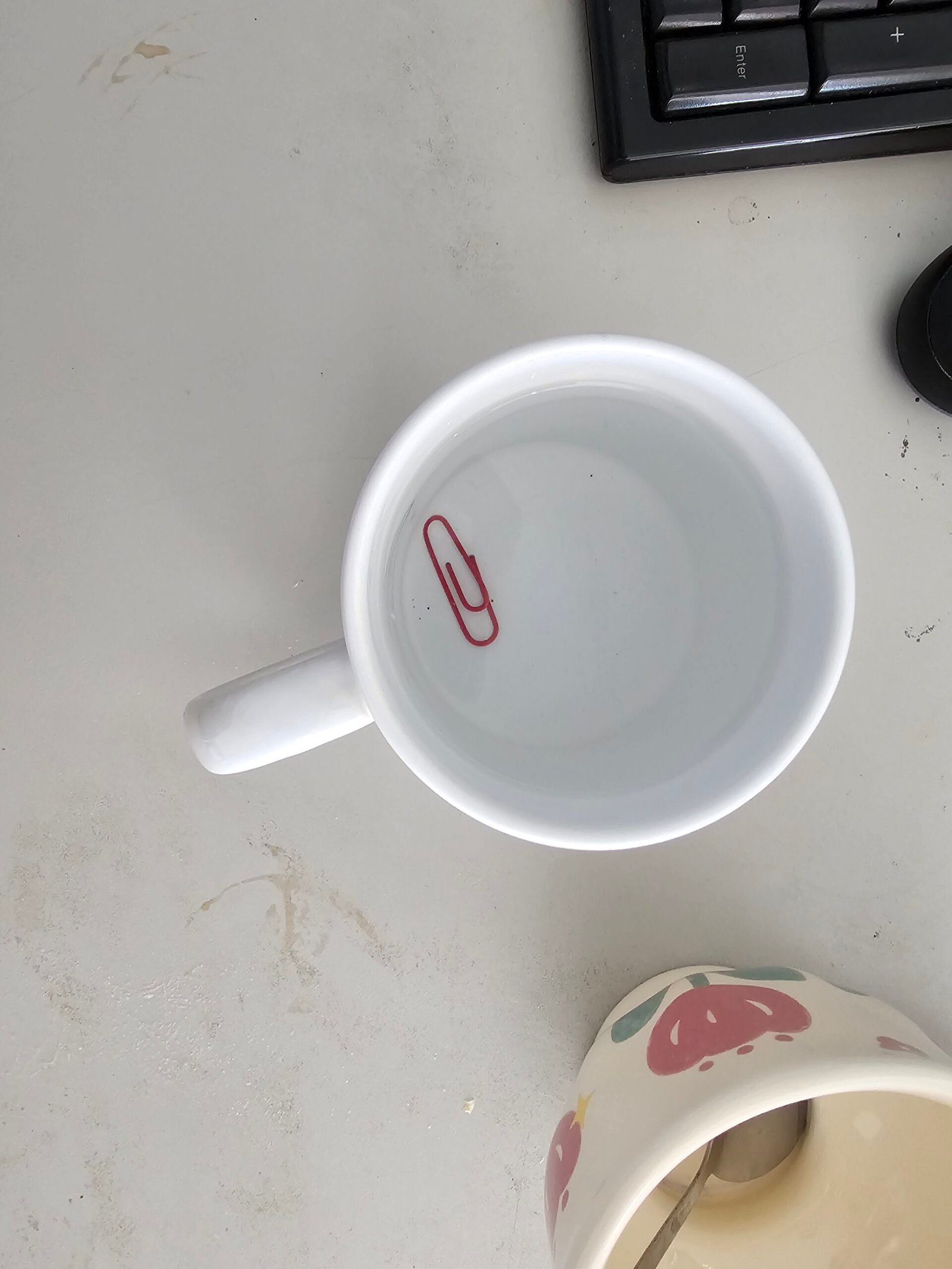 Small metal object resting on the surface of water, pressing a shallow dent into it without sinking, held up by surface tension.